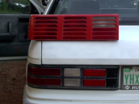 1990 Dodge Shadow - A red taillight assembly is placed on the trunk of a white car, obscuring the vehicle's actual taillights.