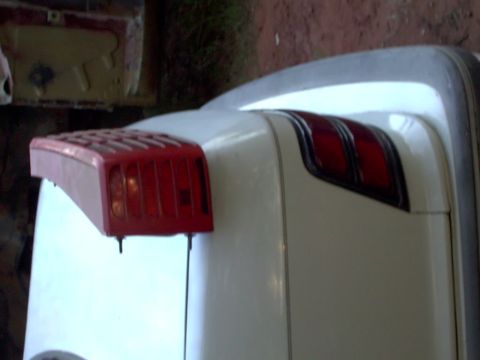 1990 Dodge Shadow - The rear of a white 1990 Dodge Shadow is shown, focusing on the tail light assembly and chrome trim.