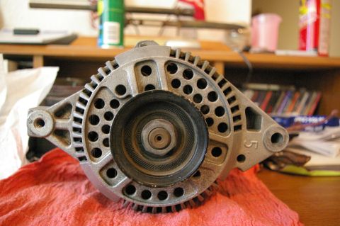 1986 Ford Bronco - An alternator is shown resting on a red cloth, with a pulley attached to its front.