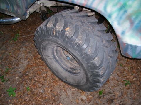 1976 Ford F-100 - Close-up of a large, knobby tire on a vehicle with a camouflage paint scheme.