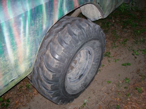 1976 Ford F-100 - A large off-road tire is mounted on a truck with a camouflage paint scheme.
