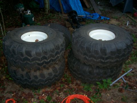 1976 Ford F-100 - Four large, tires with aggressive tread patterns are stacked in pairs on the ground.