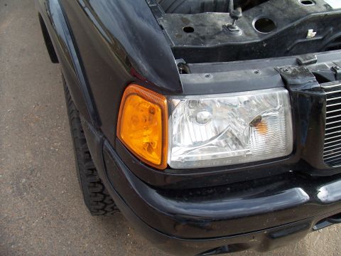 2003 Ford Ranger - Front view of a black 2003 Ford Ranger with the hood open, showing the headlight and grille.