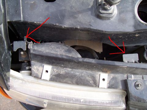 2003 Ford Ranger - Close-up view of the headlight mounting bracket on a 2003 Ford Ranger, with red arrows indicating attachment points.