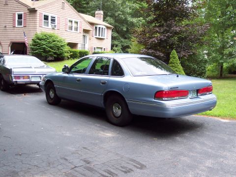 2001 Ford Crown Victoria - Light blue 2001 Ford Crown Victoria parked on a driveway, with another car and a house in the background.