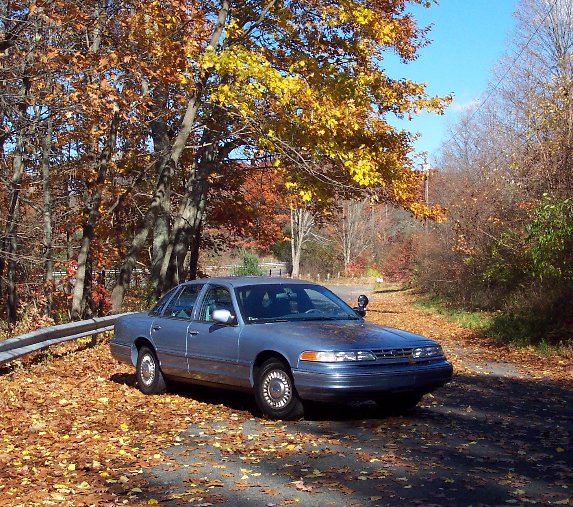 2001 Ford Crown Victoria parked on a leaf-covered road in autumn