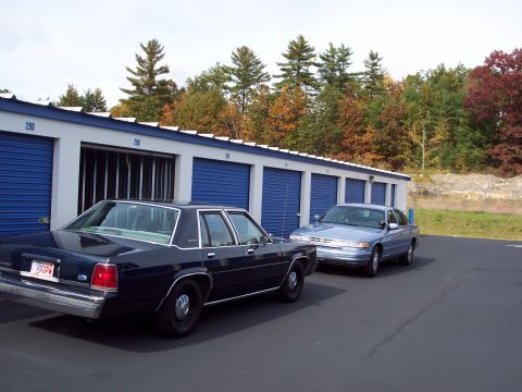 2001 Ford Crown Victoria - Two Ford Crown Victorias are parked outside a row of storage units on a cloudy day.