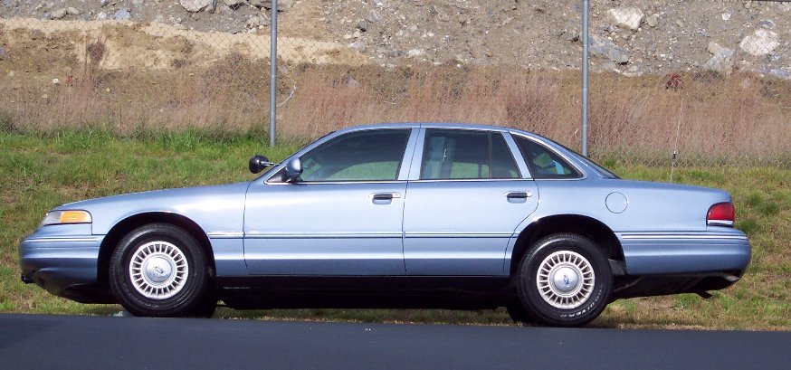 Light blue 2001 Ford Crown Victoria sedan, side view, clean condition, parked on asphalt
