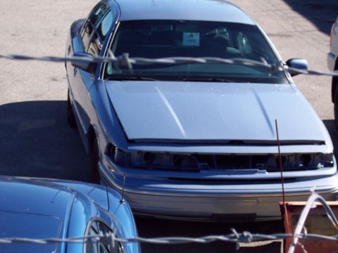 2001 Ford Crown Victoria - A light blue 2001 Ford Crown Victoria sits with its hood open, lacking a grille and headlights.