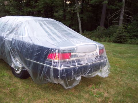 2001 Ford Crown Victoria - Rear view of a 2001 Ford Crown Victoria covered in plastic sheeting, parked outdoors on a grassy lawn.