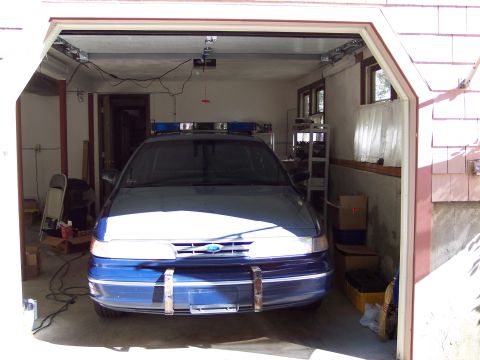 2001 Ford Crown Victoria - Police car with light bar parked in a garage.