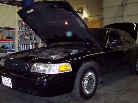 2001 Ford Crown Victoria - A black 2001 Ford Crown Victoria is parked in a garage with its hood open, revealing the engine compartment.