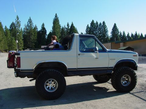 1986 Ford Bronco - This lifted Ford Bronco is shown from the side with two children riding in the open rear.