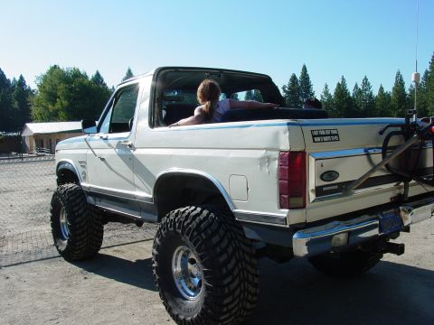1986 Ford Bronco - This lifted 1986 Ford Bronco features a removable top and aggressive off-road tires, seen from a rear angle.