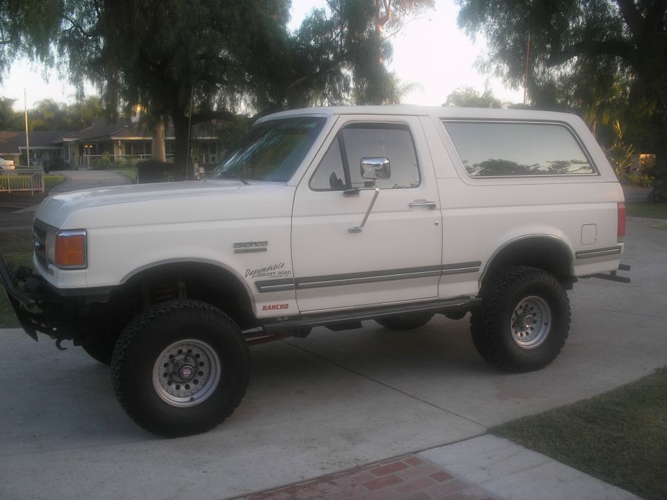 White 1990 Ford Bronco with lifted suspension and aftermarket bumper