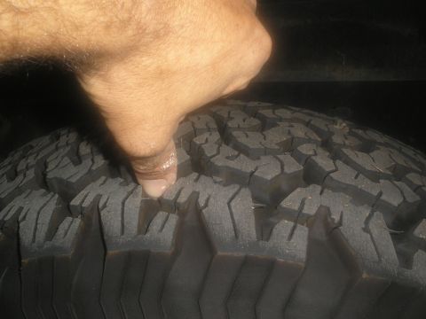 1990 Ford Bronco - A finger presses into the aggressive tread pattern of a tire, indicating wear or condition.