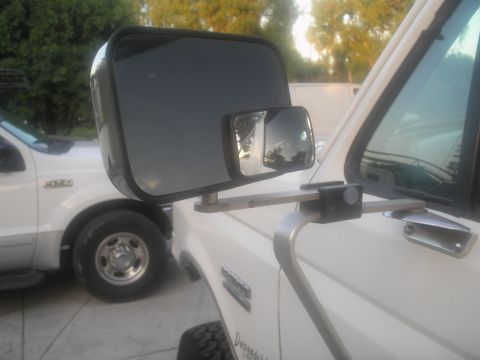 1990 Ford Bronco - Side mirror extension mounted on a white truck, with another truck in the background.