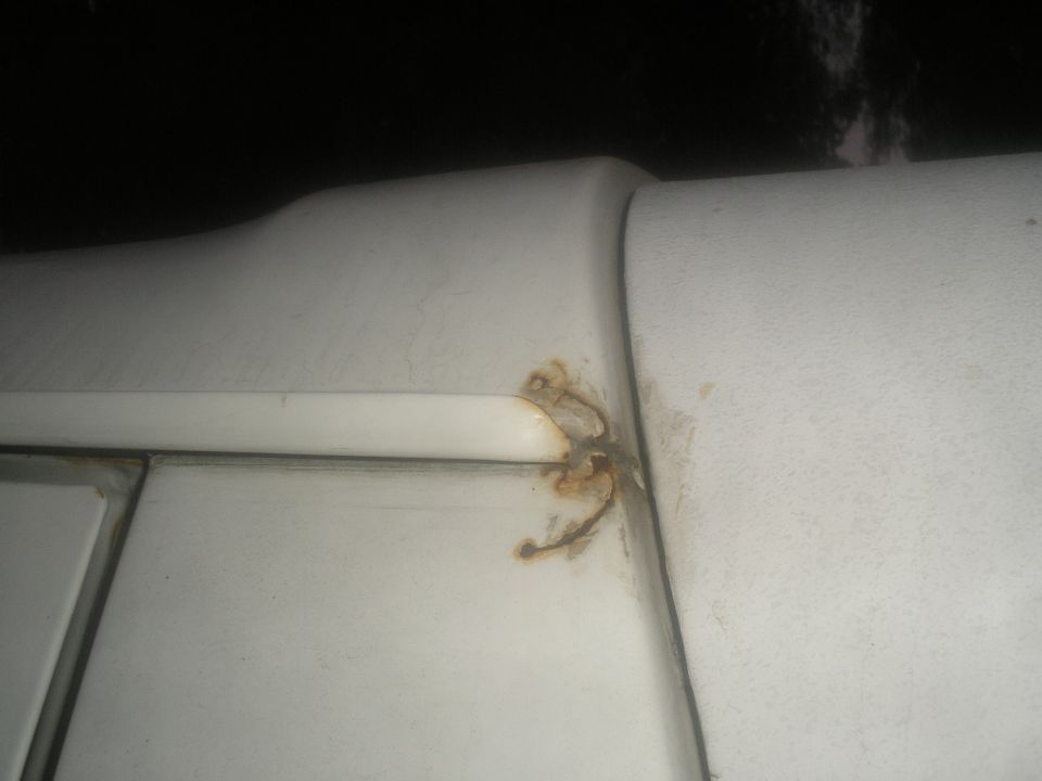 Close-up of rust forming on a white panel seam