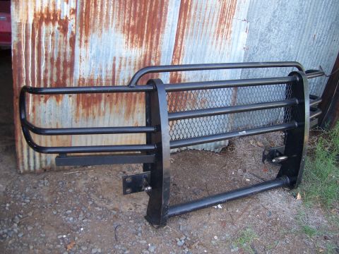 1983 Ford Bronco - A heavy-duty brush guard is shown in front of a weathered metal wall, resting on the ground.