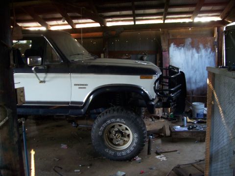 1983 Ford Bronco - A two-tone Ford Bronco is parked inside a workshop with a brush guard on the front.