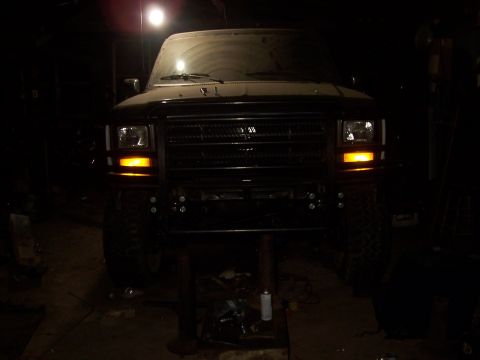 1983 Ford Bronco - Front view of a black SUV with an aftermarket bumper and grille, illuminated by a single light.