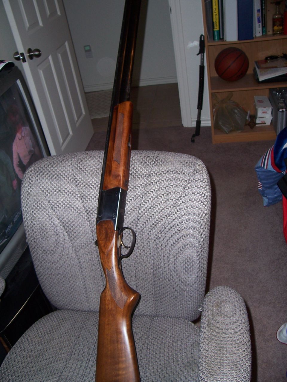 Shotgun with wooden stock and dark barrel resting on a chair