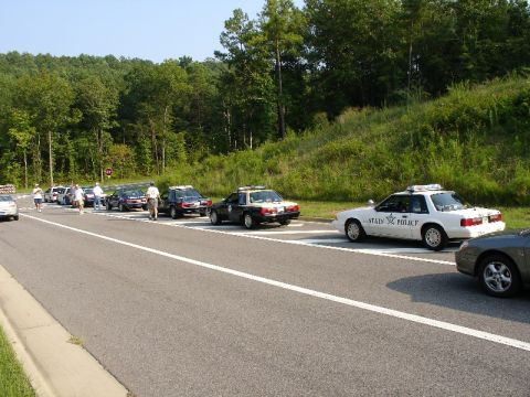 1993 Ford Mustang - A line of state police vehicles, including a 1993 Ford Mustang, are stopped on the roadside.