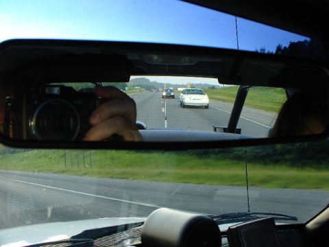 1993 Ford Mustang - A white 1993 Ford Mustang is seen in the rear-view mirror while driving on the highway.