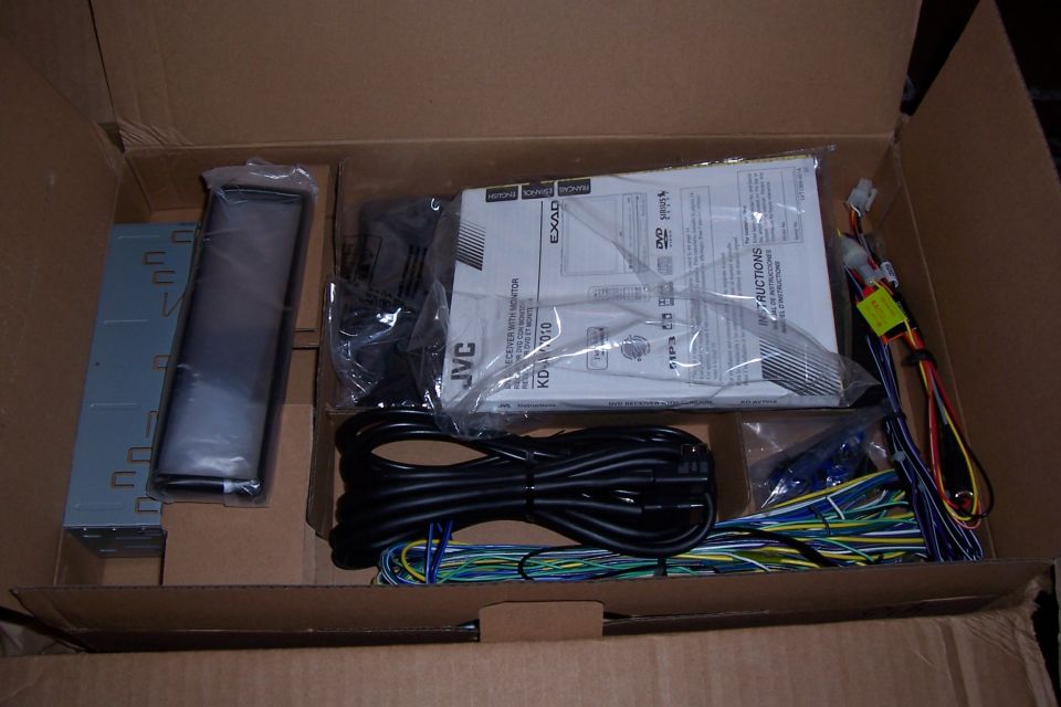 Car stereo components including JVC KD-AV7010 receiver, wiring, and manual in a cardboard box