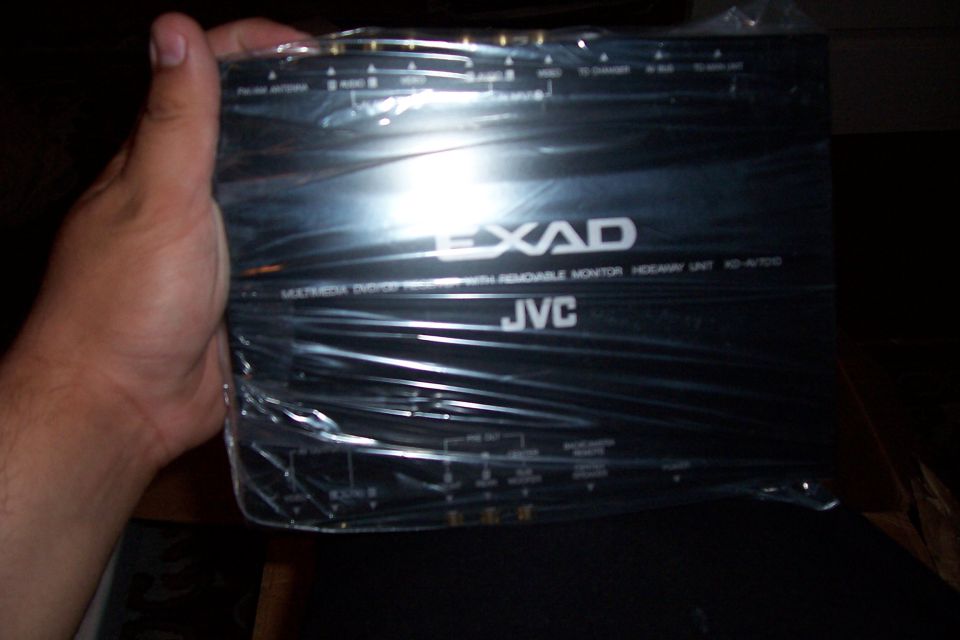 Hand holding bagged JVC EXAD KD-AV7010 DVD receiver hideaway unit