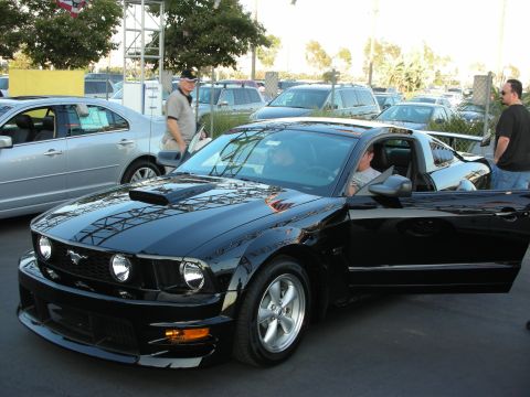 1998 Ford Crown Victoria - A black Ford Mustang is parked with its passenger door open, showing the interior and driver.