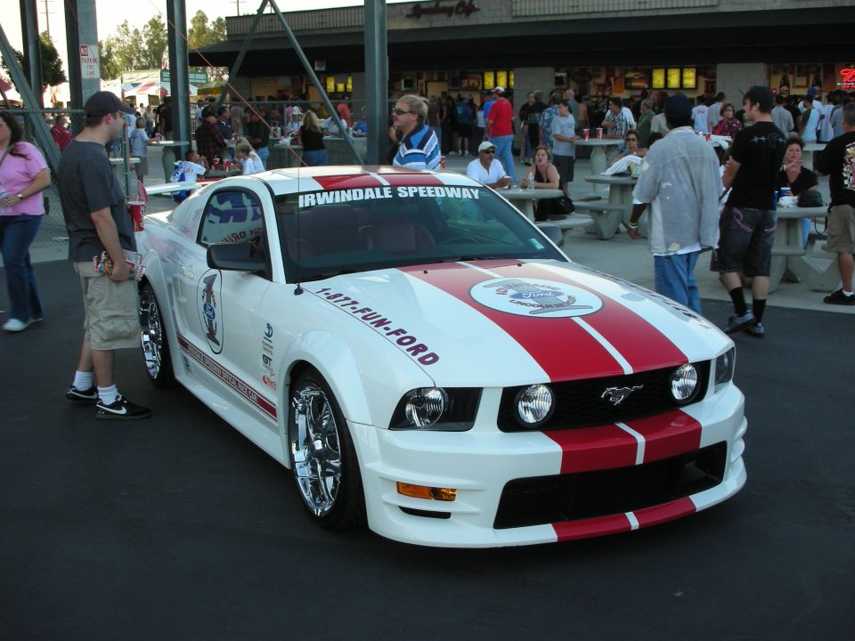 White and red Mustang with Irwindale Speedway windshield banner at an event