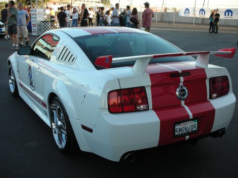 1998 Ford Crown Victoria - Rear view of a white 2005 Ford Mustang GT with red racing stripes and a large rear spoiler.
