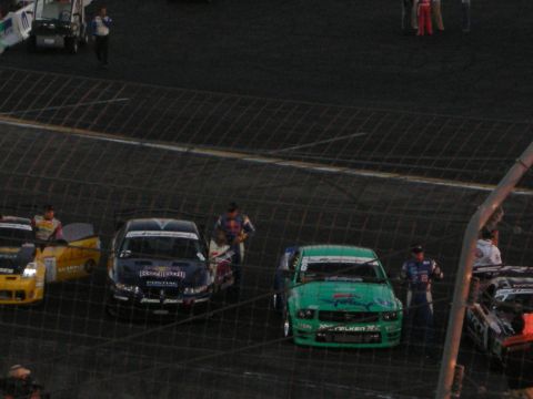 1998 Ford Crown Victoria - Cars and crew members are gathered on the track, possibly before or after a race event.
