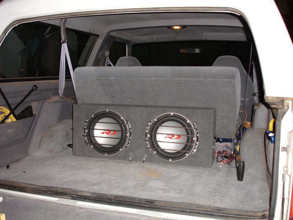 Dual RD subwoofers in carpeted box mounted in cargo area of white SUV with rear seat folded