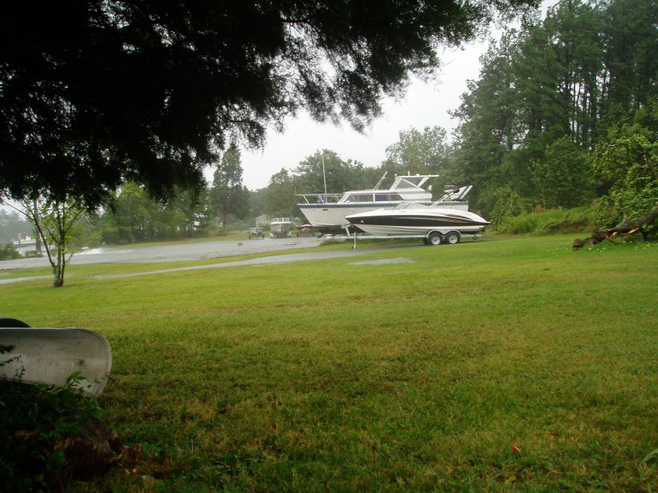 Two boats on trailers parked on a grassy area near trees