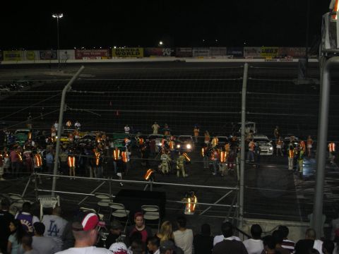 1998 Ford Crown Victoria - A 1998 Ford Crown Victoria is visible on the track among other vehicles and spectators during a night event.