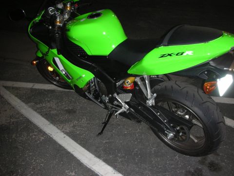 1998 Ford Crown Victoria - A bright green motorcycle, identified as a ZX-6R, is parked in a lot at night.