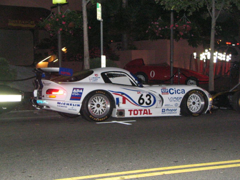 White race car with number 63, sponsors like Total and Michelin. Red car in background