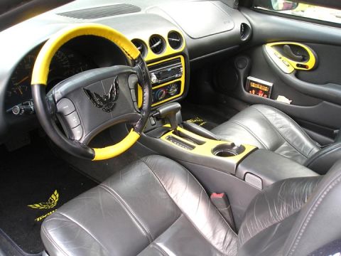 1984 Pontiac Fiero - Interior view of a car with yellow trim and a bird emblem on the steering wheel.