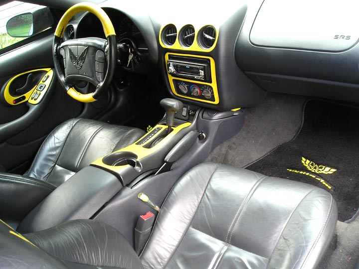 Car interior with black leather seats and yellow trim on dashboard and steering wheel