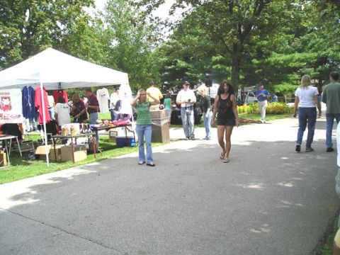 1984 Pontiac Fiero - People milling about at an outdoor event with vendor tents set up.