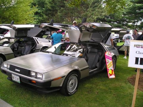 1984 Pontiac Fiero - DeLorean DMC-12 cars displayed at a car show, some with gullwing doors open.