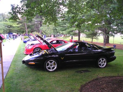 1984 Pontiac Fiero - A black Pontiac Firebird is displayed at an outdoor car show with its hood open.