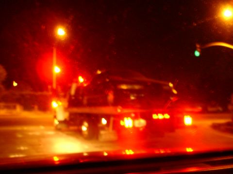 1993 Ford Taurus - A car is loaded onto a tow truck at night, with its red taillights illuminated.
