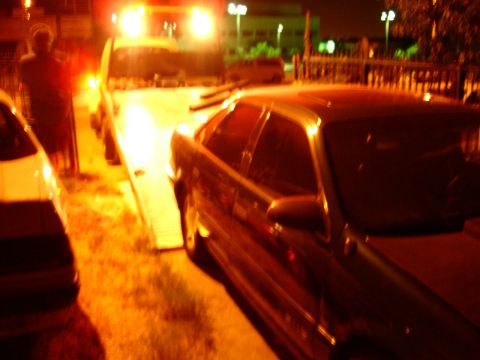 1993 Ford Taurus - A 1993 Ford Taurus is loaded onto a tow truck at night.