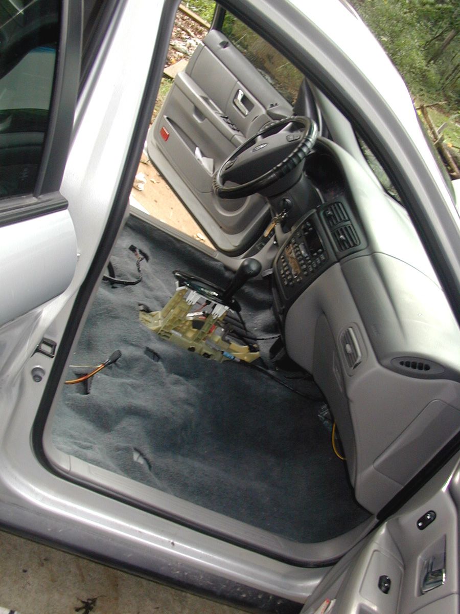 Ford sedan front interior with seats and console removed, loose wiring block on carpet