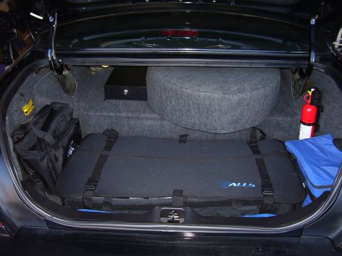 2002 Ford Crown Victoria - The trunk of a 2002 Ford Crown Victoria contains a spare tire, fire extinguisher, and various bags and luggage.