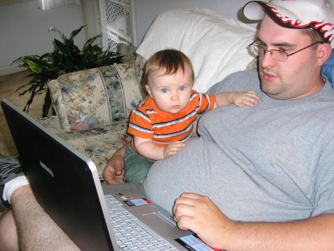 1998 Ford Taurus - Man and baby interact with a laptop computer while sitting on a couch.