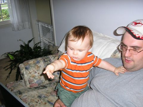 1998 Ford Taurus - A man and a baby are sitting on a couch in a living room.